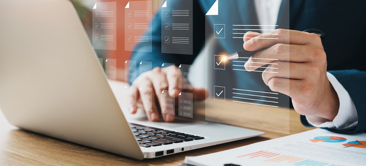 A man check marks a document on his laptop