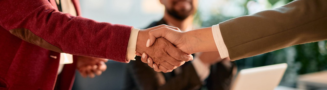 Two businesspeople shaking hands over a conference table