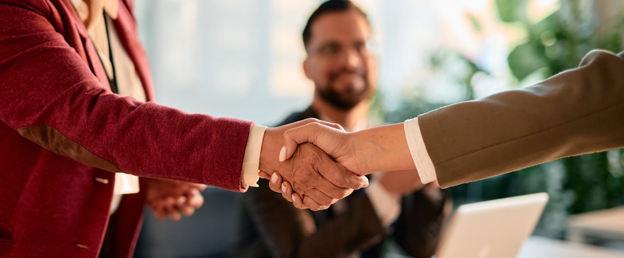 Two businesspeople shaking hands over a conference table