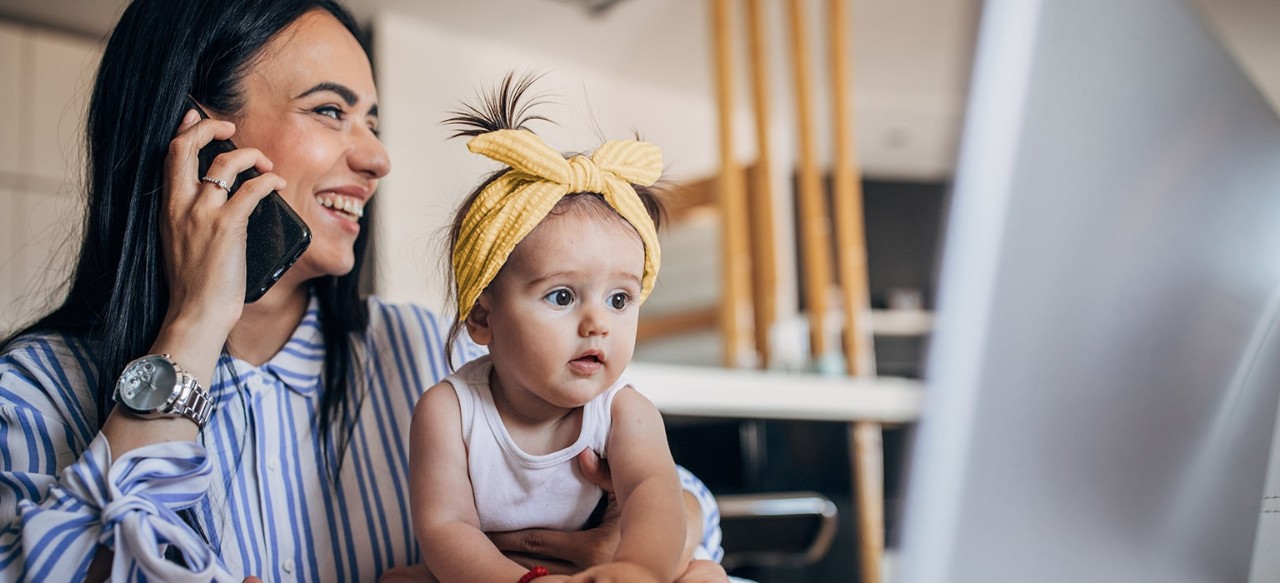 Mother on phone call, holding baby daughter wearing yellow bandana