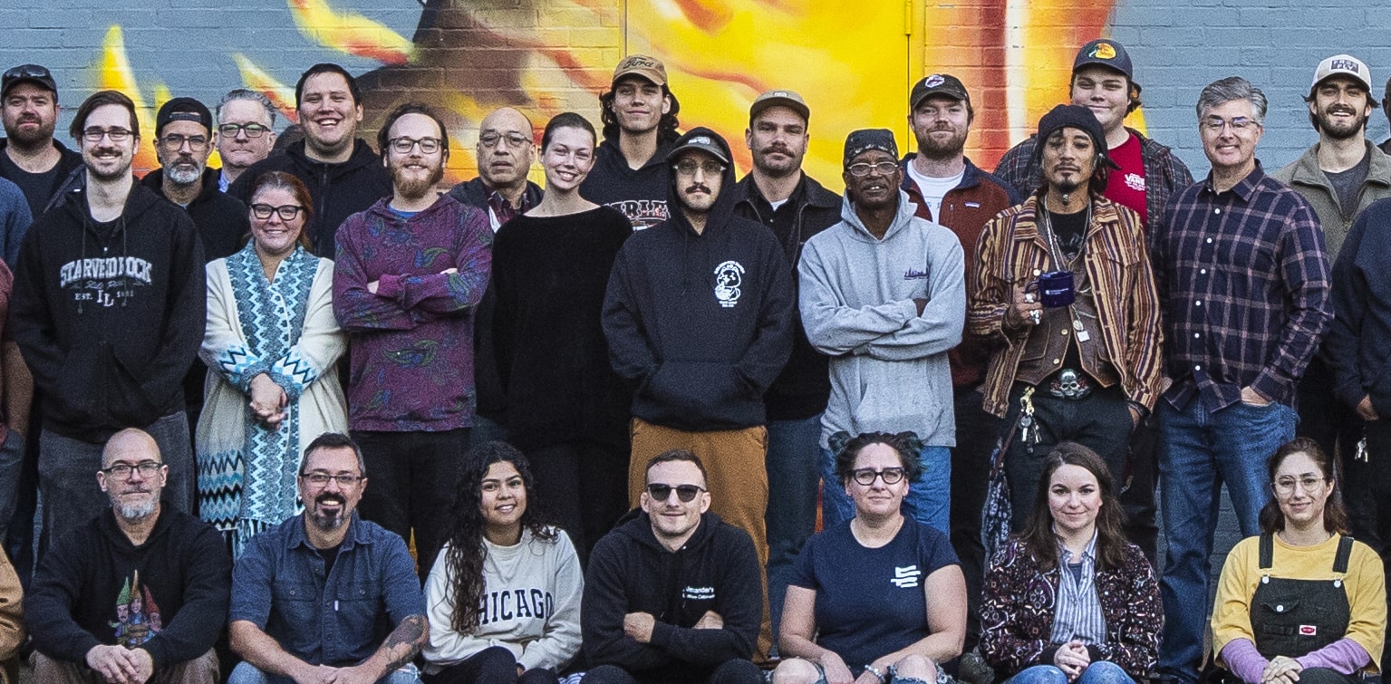 A group photo of the Bridgewater company in front of a mural