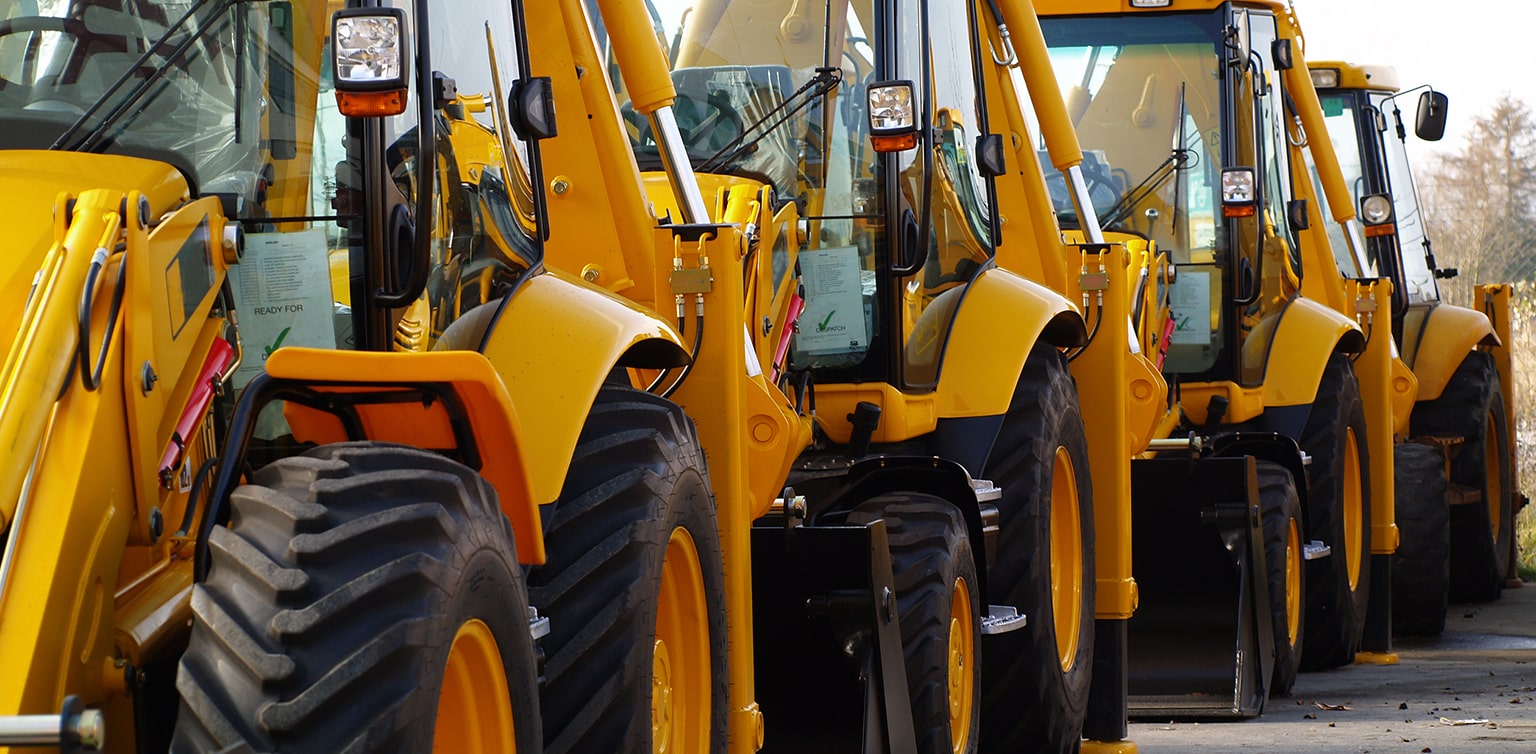 Several backhoe loaders in single-file line