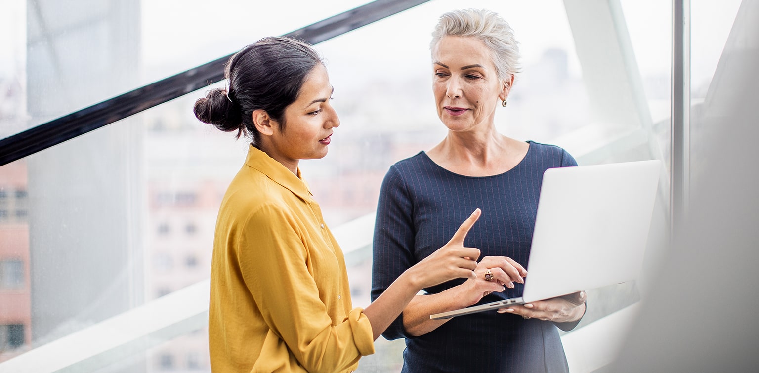 Two businesswomen reviewing information on a laptop