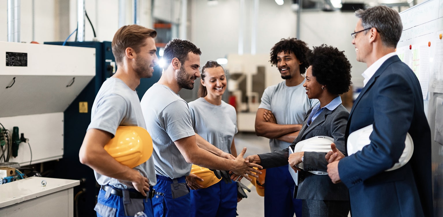 Employees with hard hats meeting with bankers in warehouse facility