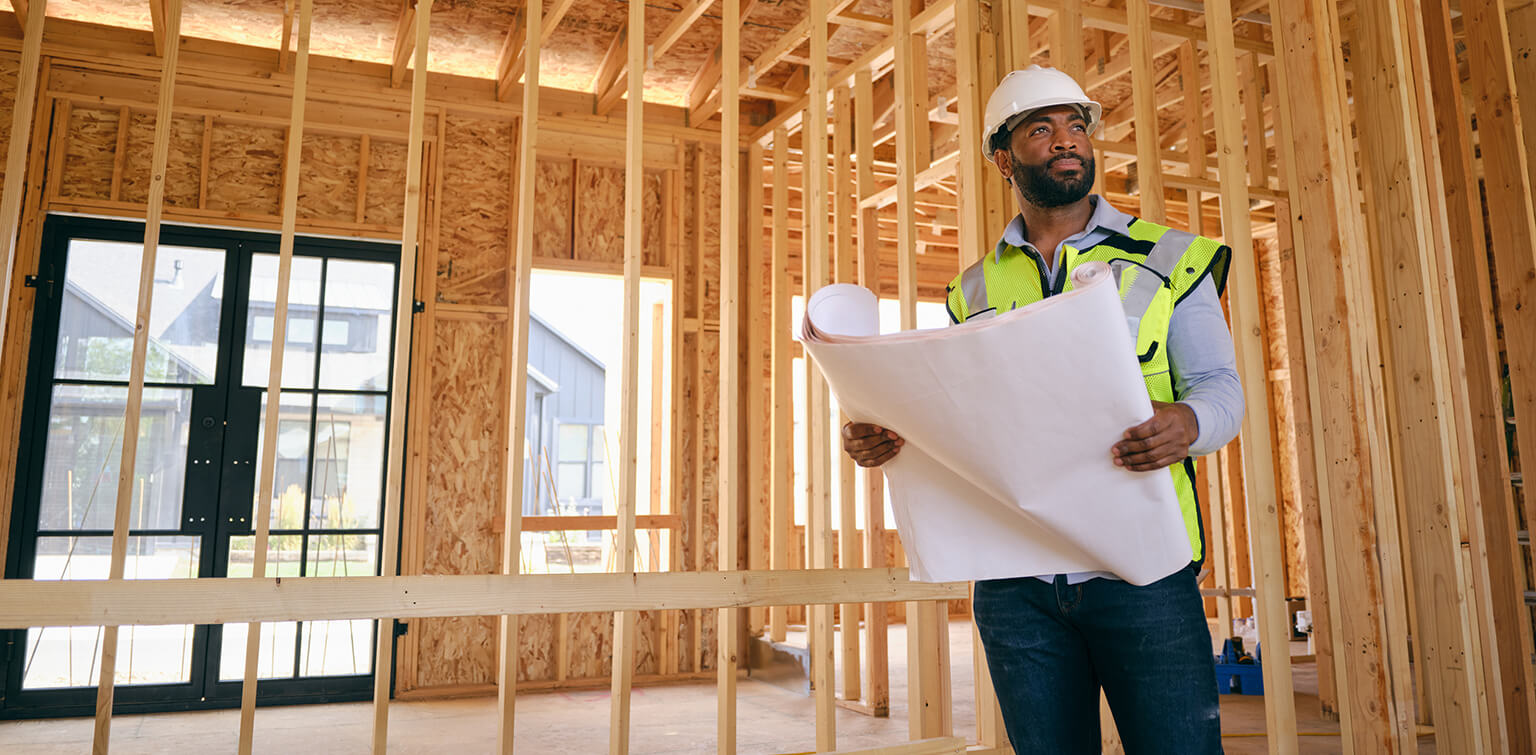 business owner holding blueprints at construction site