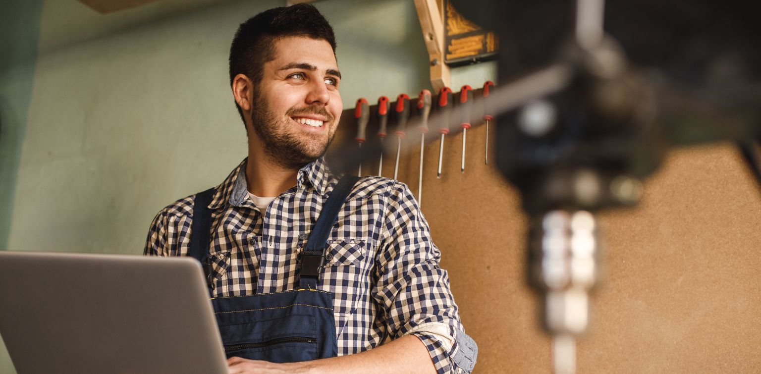 Smiling small business owner surrounded by tools in workshop