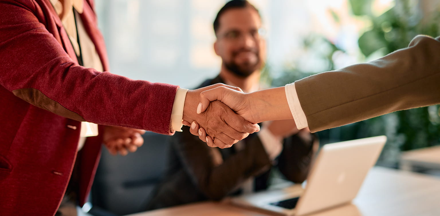 Two businesspeople shaking hands over a conference table
