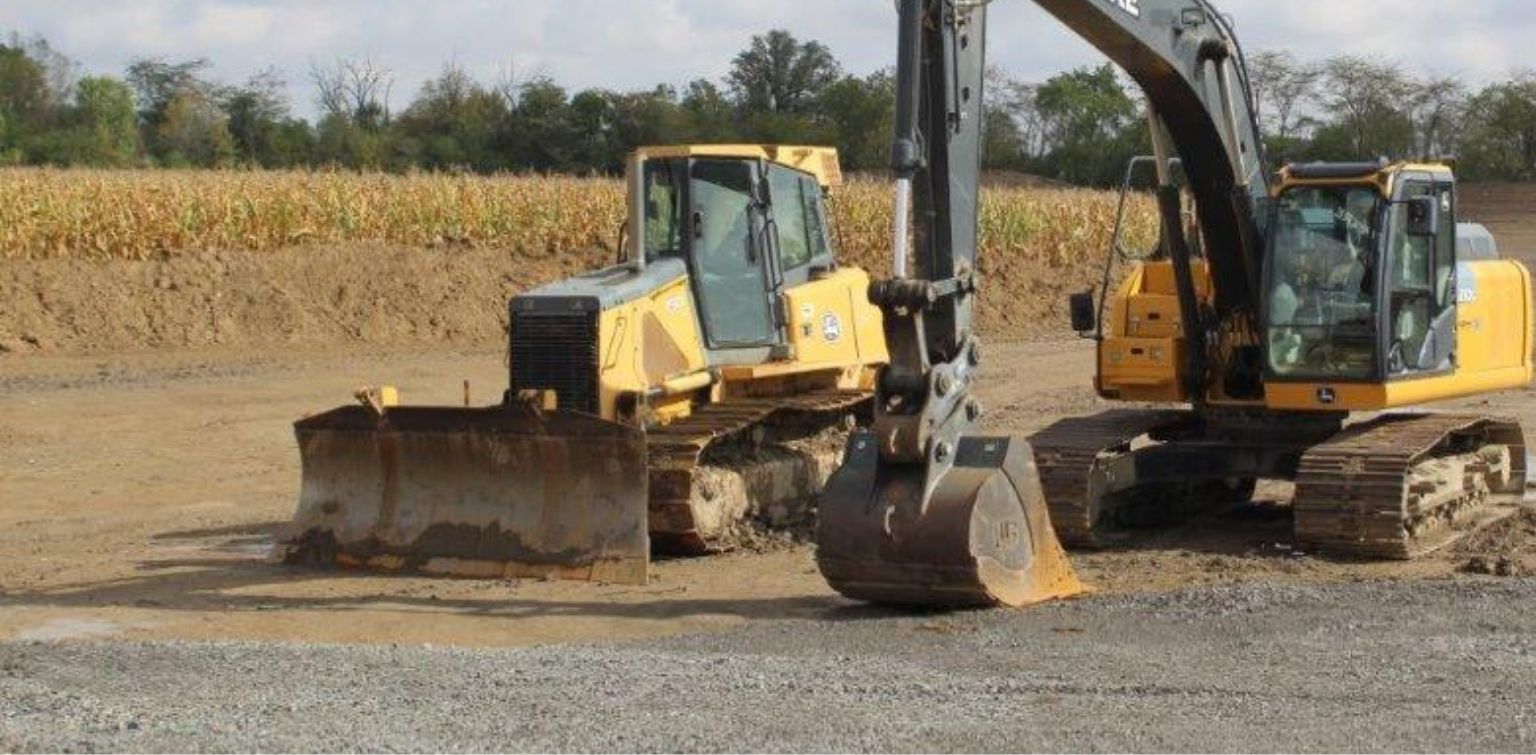 Heavy equipment including a bulldozer and excavator sitting in a field