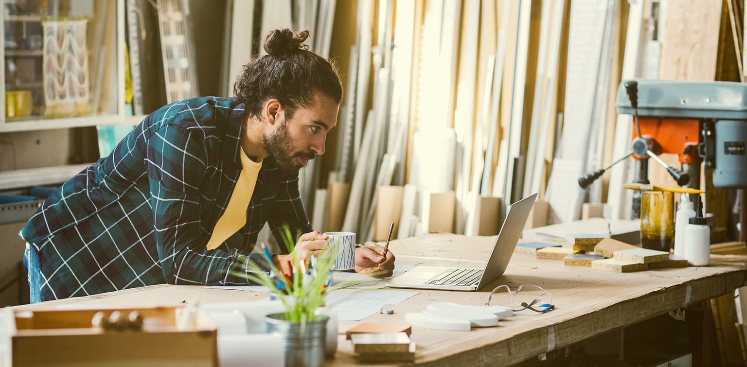 Lumber company business owner leaning on desk looking at laptop