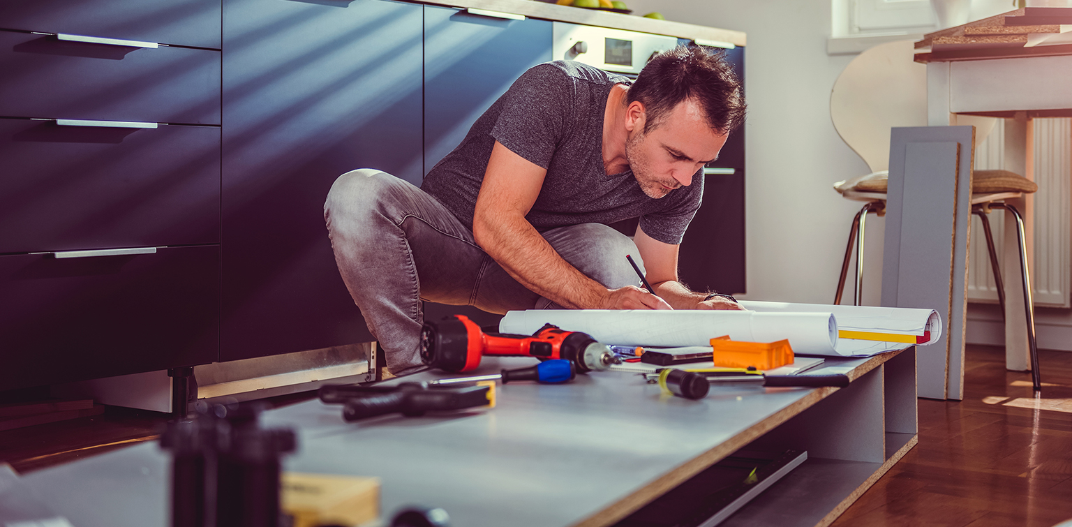 Man working on a new kitchen installation and looking at blueprints