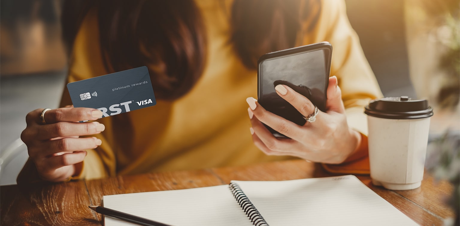 Asian woman holding First Financial credit card and looking at smartphone