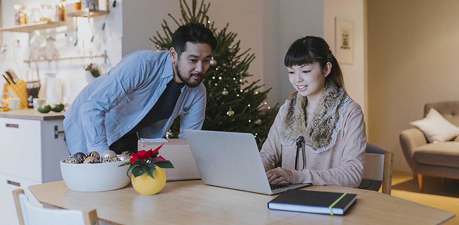 Asian couple at kitchen table looking at desktop during holidays