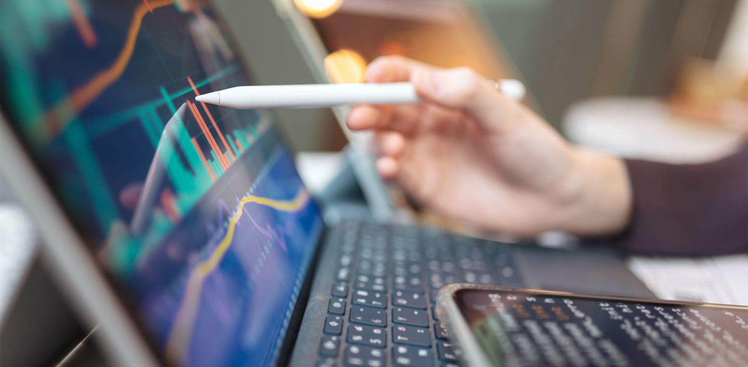 Person pointing a stylus at a digital display of financial data