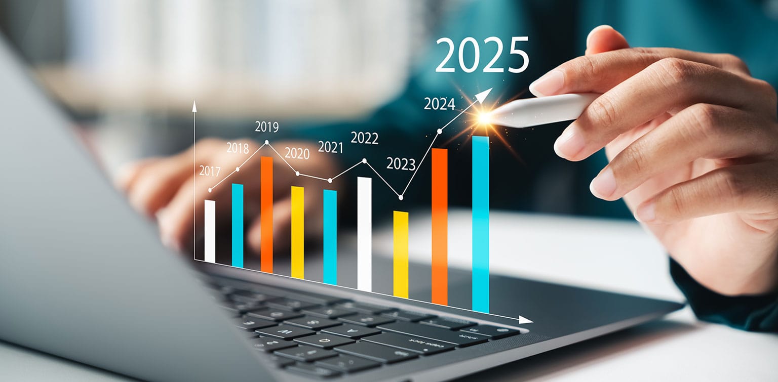 A person's hands using a laptop with an upward trending year-over-year financial graph