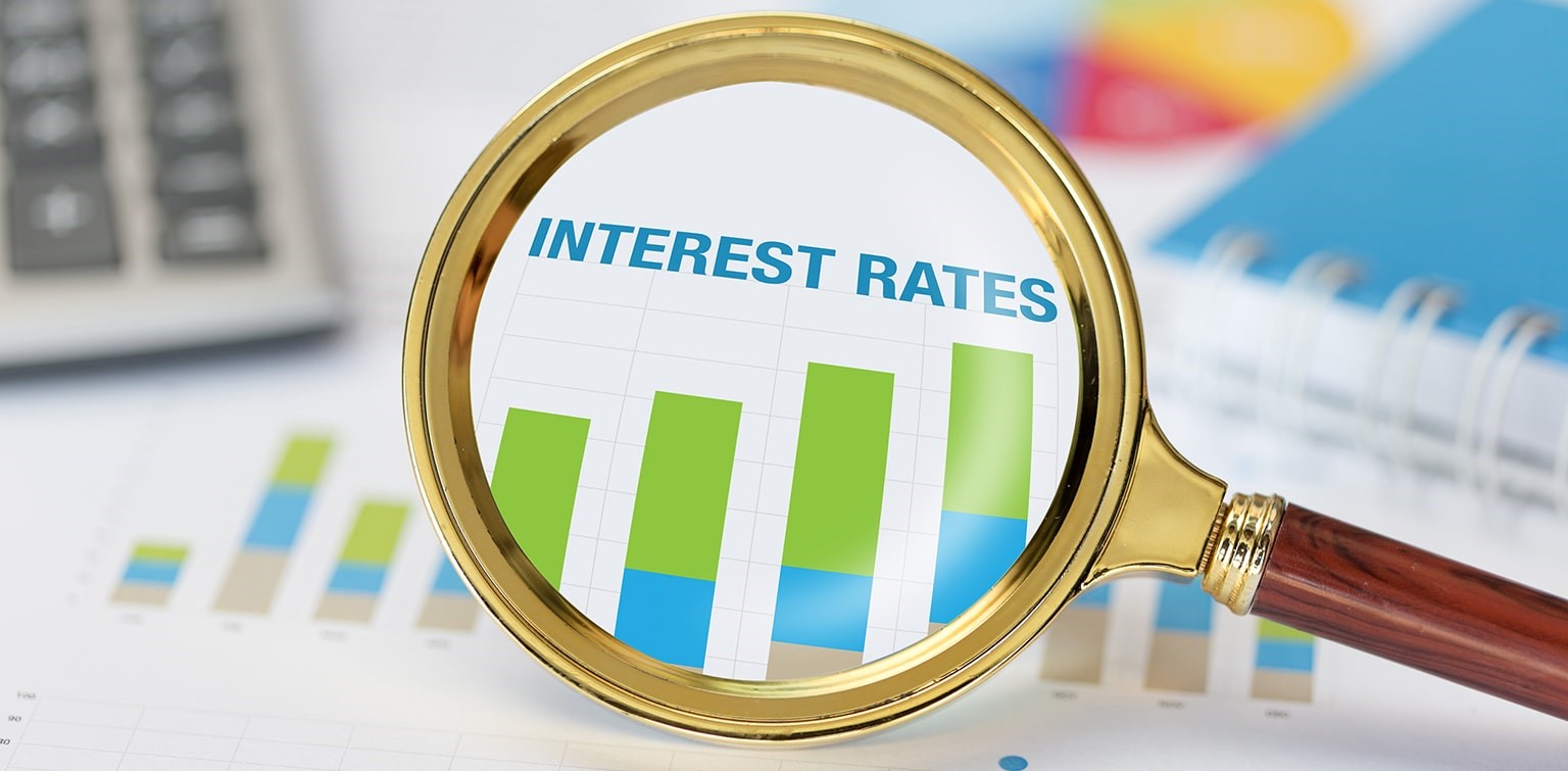 Magnifying glass and calculator on chart displaying increasing interest rates