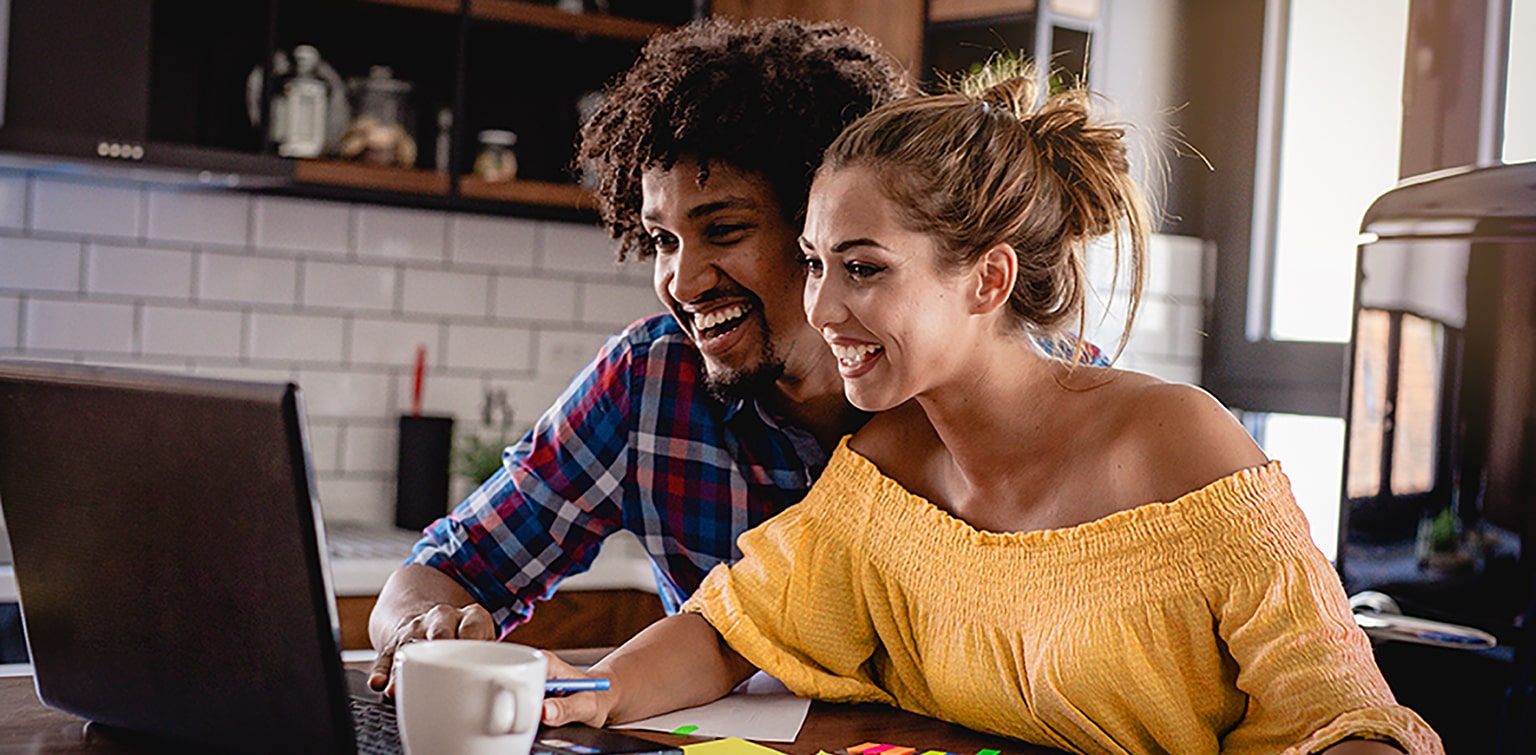 Multiracial couple at table looking at laptop