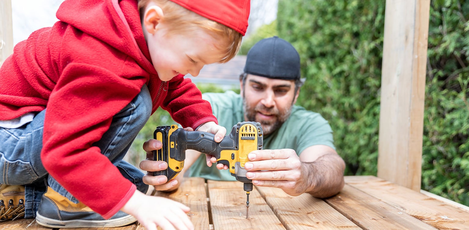 Man and child operating power tools