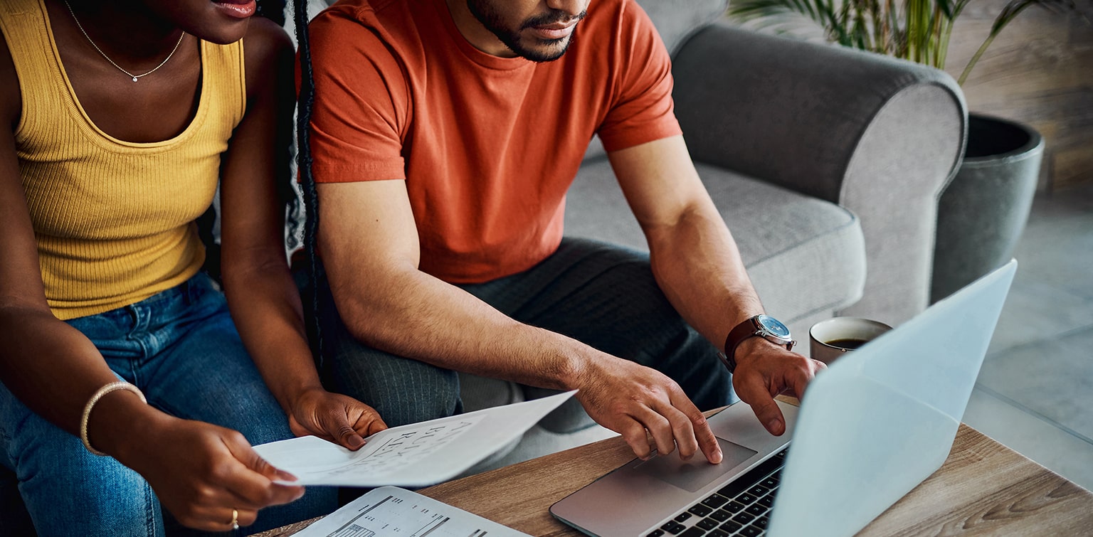 African-American couple using laptop and reviewing financial documents