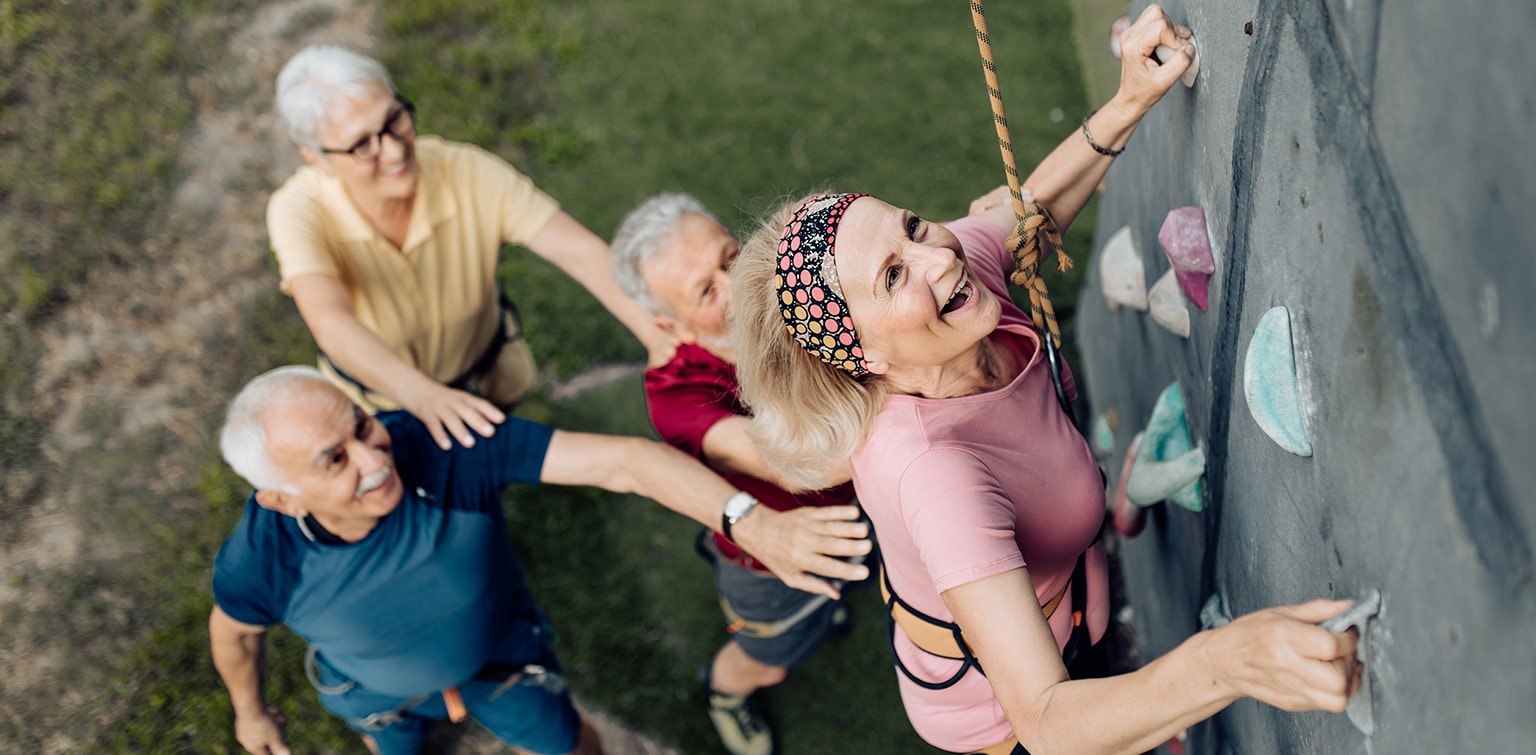 Retired people enjoying climbing a rock wall after applying for Social Security benefits