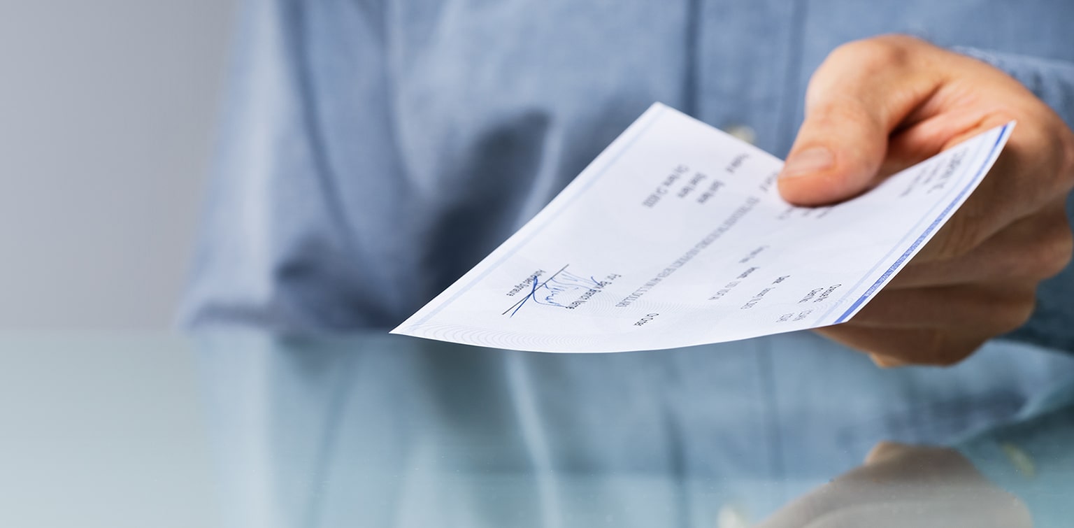 Man holding a check as he hands it to another person