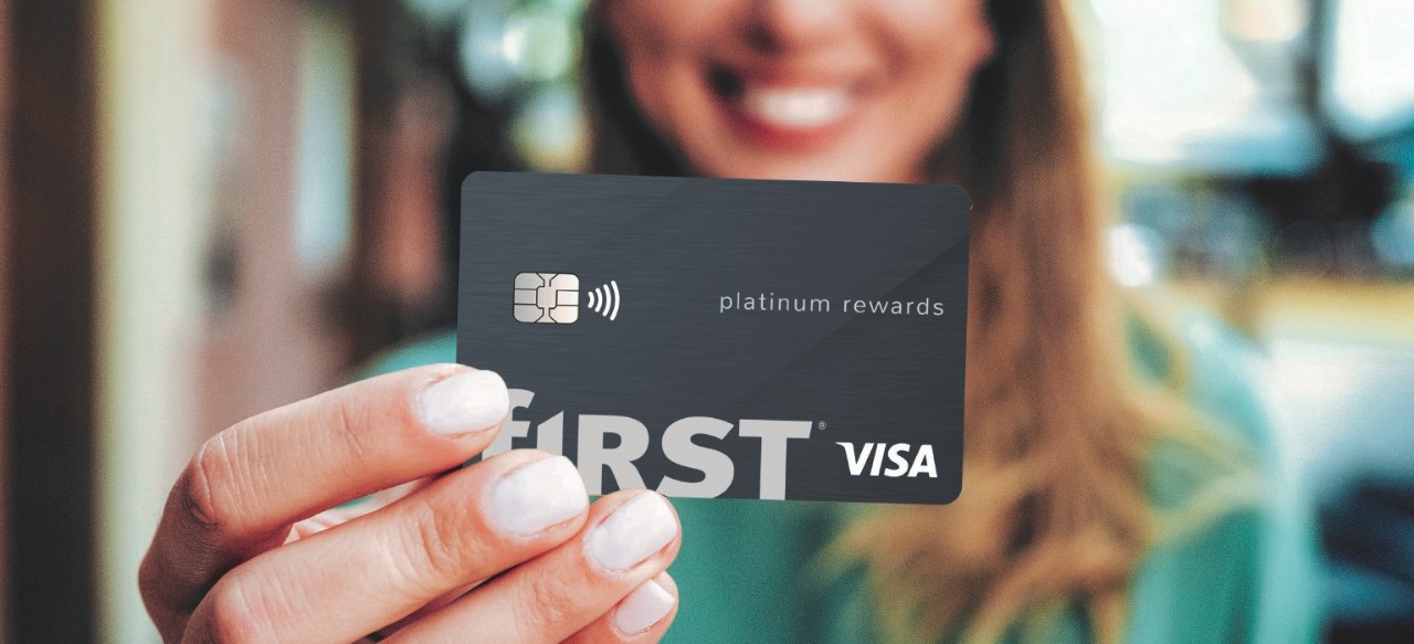 smiling woman holding a First Financial Bank credit card with her two fingers