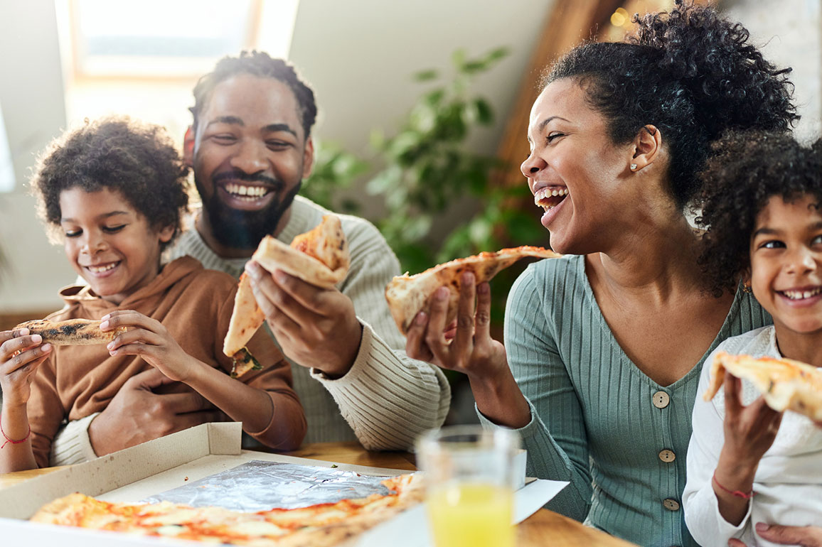 Happy African-American family eating pizza