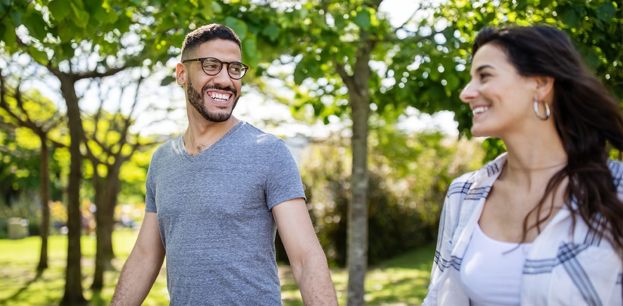 Two people holding hands while walking through a park.