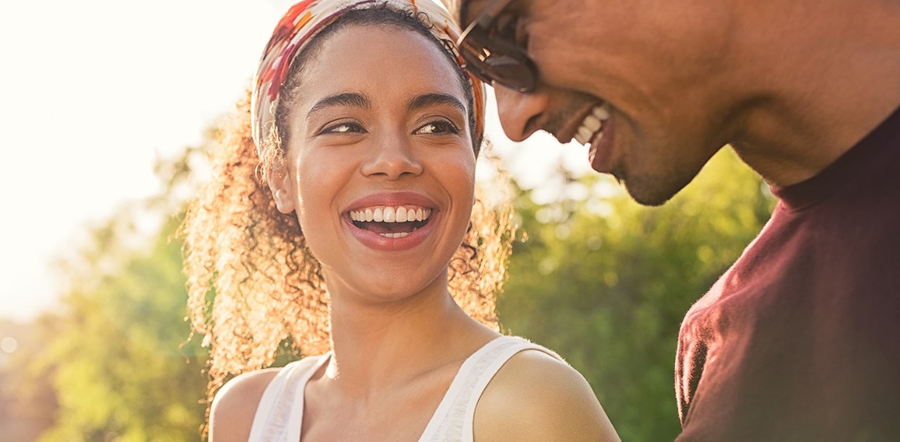Two people outdoors smiling while one holds her phone.