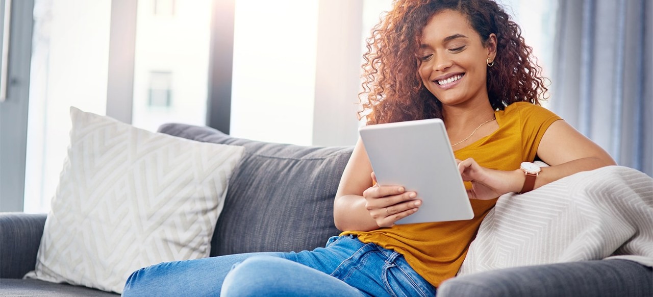 Lady relaxing on couch, looking at tablet