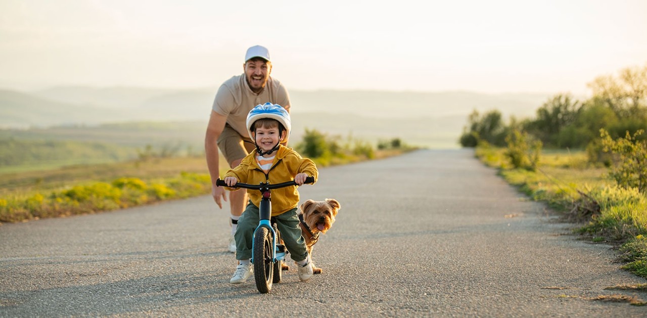 Father with small dog and young son riding bicycle