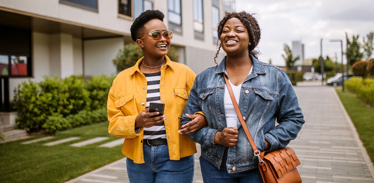 Two smiling African-American women walking and chatting