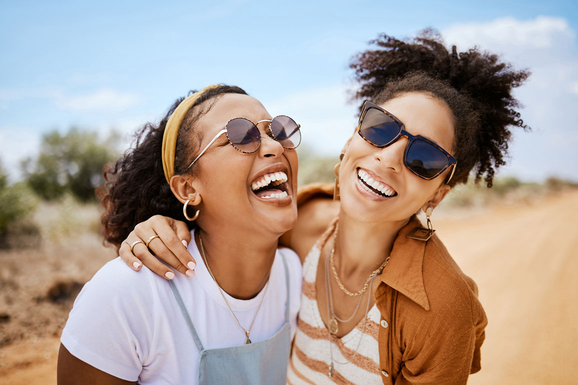 Two young African-American women smiling and hugging