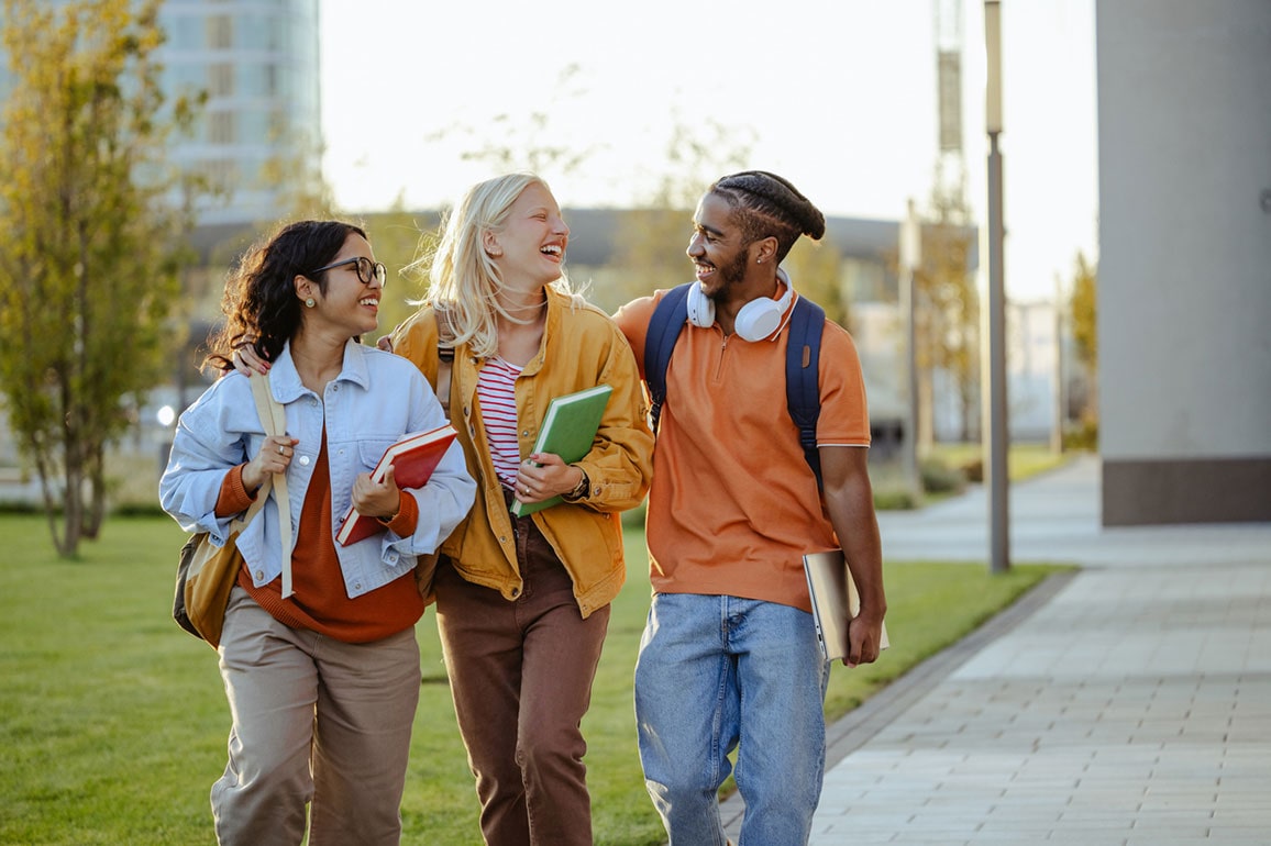 Three diverse college students walking and chatting