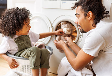 Father and young child doing laundry