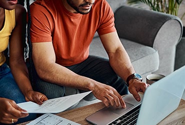 African-American couple using laptop and reviewing financial documents