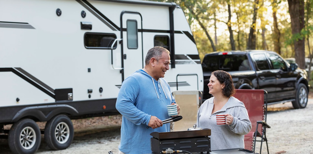 Middle-aged couple cooking on a camp stove in front of their RV