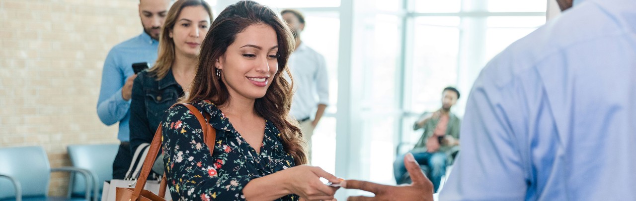Young female bank client handing card to banker