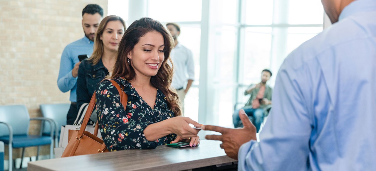 Young female bank client handing card to banker