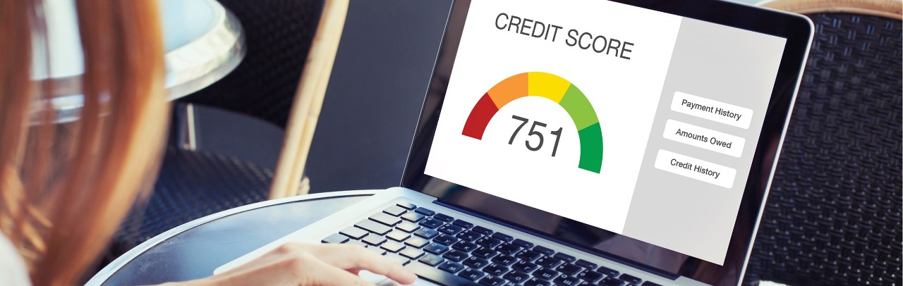 A woman typing at a laptop that has a credit score of 751 displayed