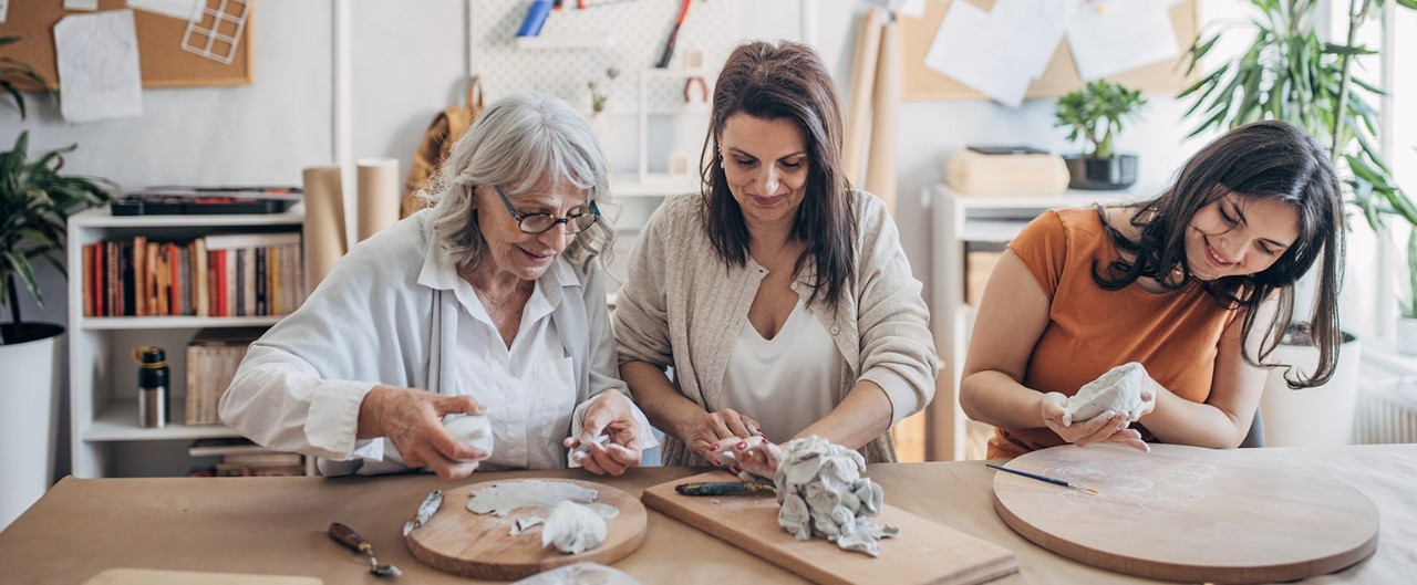 Woman working on pottery project with her mother and teenaged daughter