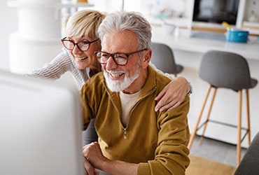 Senior couple smiling and looking at computer monitor