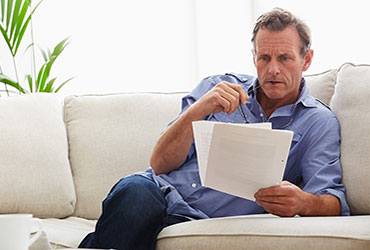 Middle-aged man reviewing documents on sofa