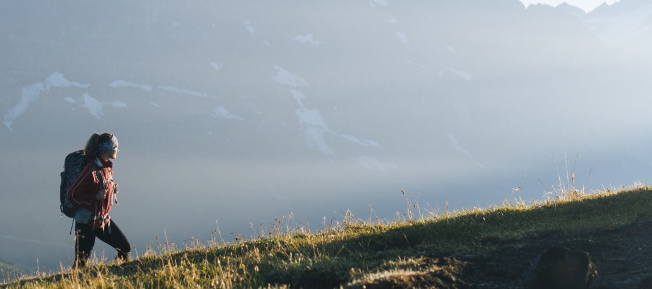 Woman hiking in a meadow with mountains in the background